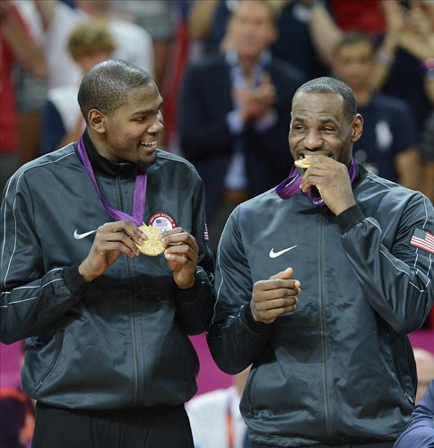 USA guard Kevin Durant watches USA forward LeBron James bite the gold medal